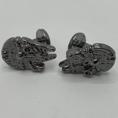 Boutons de manchette en métal argenté, en forme de Millenium Falcon. Produit vendu en ligne.