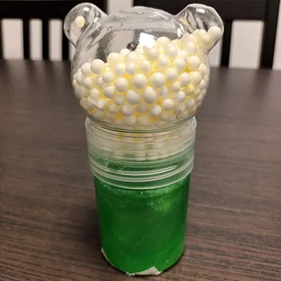 Slime de jouet vert. Livré avec de petites boules colorées, dans un compartiment séparé.