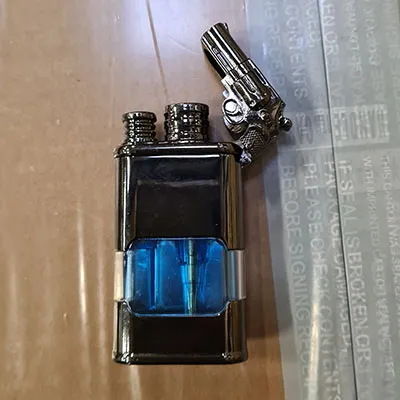 Briquet en métal avec horloge intégrée. Au-dessus du briquet, il y a un petit pistolet attaché.