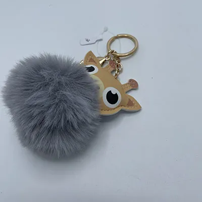 Jouet en peluche, en forme de tête de girafe et de pompon gris, avec porte-clés.