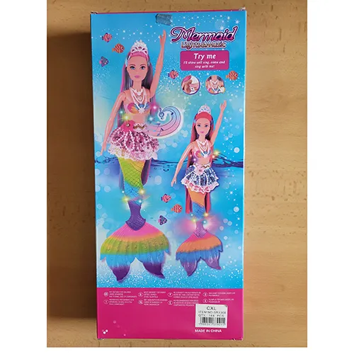 Poupée avec de longs cheveux colorés, une jupe en dentelle avec des perles en plastique, un corsage en plastique coloré, des perles en plastique sur son cou et une nageoire de poisson. Le produit comprend également un dauphin en plastique rose ou bleu, une brosse à cheveux, des coquillages, des palourdes et une étoile de mer. Taille : 39 cm.