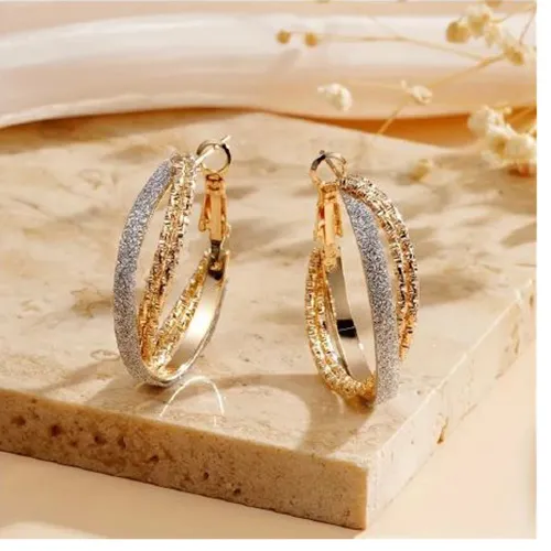 Paire de boucles d'oreilles croisées en métal doré avec une bande non métallique de paillettes collée à un anneau. Tous les lots sont concernés. Produit vendu en ligne, notamment via TEMU (identifiant unique du produit: 601099582004796).