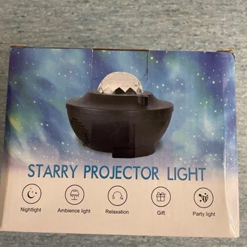 Lumière du projecteur sous la forme de nébuleuses galactiques en mouvement et d'un ciel étoilé. Les nébuleuses galactiques sont projetées via un hémisphère cristallin transparent dans la partie supérieure du projecteur. Produit vendu en ligne, notamment via Kaufland.de