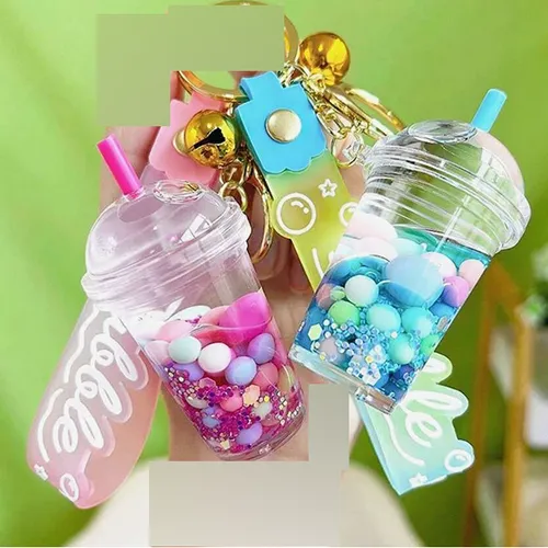 Trois porte-clés avec une figure de tasse à thé à bulles. La figurine en plastique contient deux liquides non mélangeables (roses et transparents) dans des récipients scellés par un bouchon en plastique en caoutchouc. Produit vendu en ligne, notamment via Shein (identifiant produit, SKU: sc2407277808880181).
