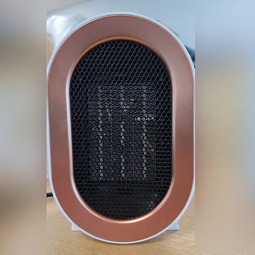 Chauffage de ventilateur blanc de forme ovale avec une grille noire et un cordon d'alimentation noir attaché. Produit vendu en ligne, notamment via Amazon (ASIN: B0CMCZT6QR).