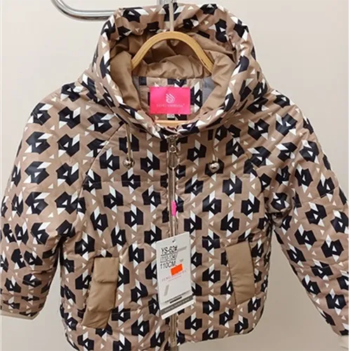 Veste destinée aux jeunes enfants, avec un dessus en tissu de couleur crème matelassé de rayures horizontales, imprimé avec des figures noires et blanches régulières. La capuche utilise un cordon élastique fonctionnel sous la forme d'une boucle, les extrémités des boucles dépassent librement d'environ 7 cm.