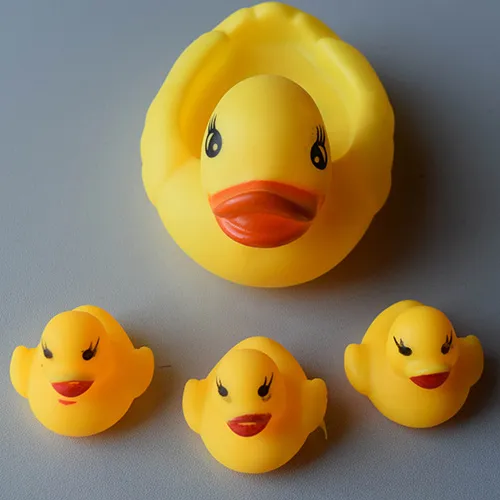 Famille de canards jouets en plastique jaune composée d'un canard plus grand et de trois canards plus petits.