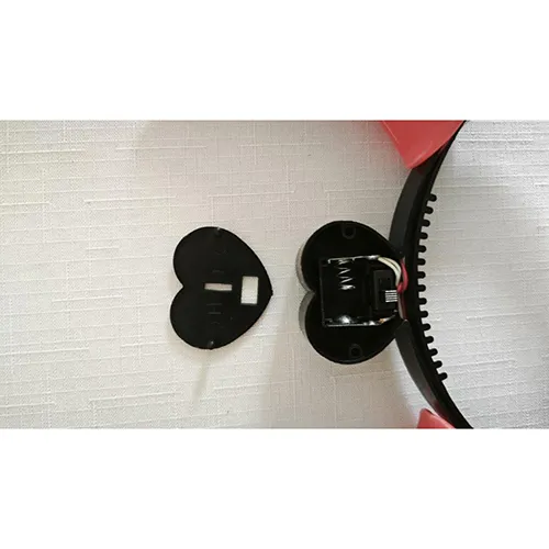 Bandeau en plastique brillant en forme de cornes de diable, à piles. Au milieu du bandeau se trouve un couvercle en forme de cœur pour deux piles AG13.