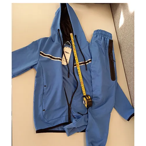 Ensemble de vêtements pour enfants destiné aux jeunes enfants, en tissu tricoté bleu clair. Il est composé d'un pull avec capuche, fermeture éclair et poches encastrées. La capuche a un cordon textile fonctionnel avec des extrémités libres d'environ 24 cm de long. Il comprend également une paire de pantalons en tricot textile bleu clair et avec des poches encastrées.