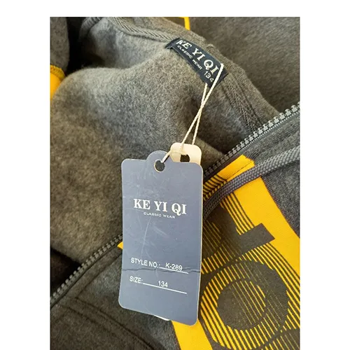 Ensemble de vêtements destinés aux jeunes enfants, en tissu tricoté gris. Il comprend un sweat-shirt avec capuche, fermeture à glissière et poches encastrées. La capuche a un cordon textile fonctionnel avec des extrémités libres, d'environ 28 cm de long. Il comprend également une paire de pantalons en tricot textile bleu clair et avec des poches encastrées.