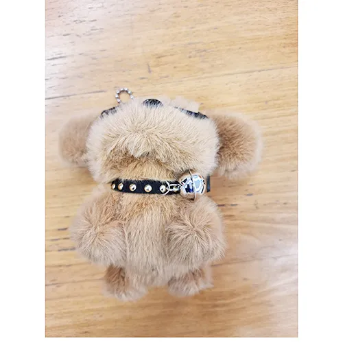 Jouet en peluche, en forme de chiot brun avec des lunettes noires et un collier avec une cloche. Produit vendu en ligne, notamment via Shein.