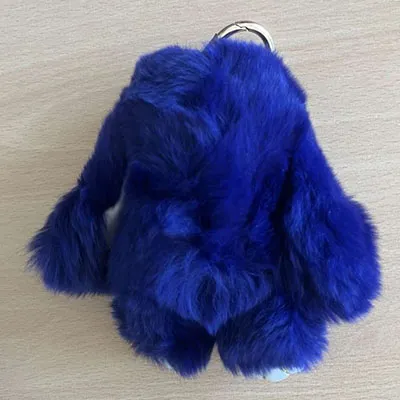 Porte-clés en peluche bleu en forme de lapin avec des pattes en cuir noir et un anneau métallique de couleur dorée. Produit vendu en ligne, notamment via Amazon (ASIN: B0DM5C9786).