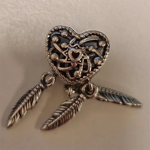 Bracelet en forme de coeur avec plumes. Produit vendu en ligne, notamment via AliExpress.