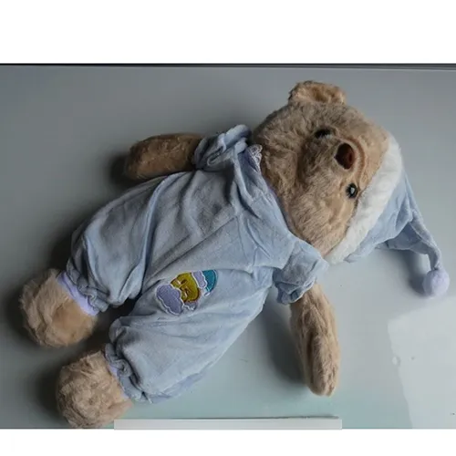 Jouet doux en forme d'ours aux yeux en plastique noir, vêtu d'un pyjama bleu et d'un bonnet de nuit assorti. Produit vendu en ligne, notamment via TikTok.