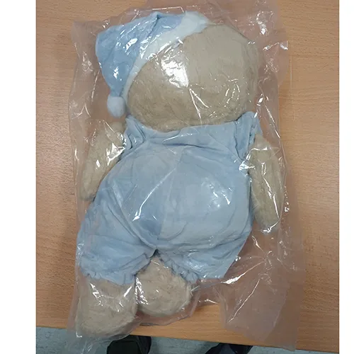 Jouet doux en forme d'ours aux yeux en plastique noir, vêtu d'un pyjama bleu et d'un bonnet de nuit assorti. Produit vendu en ligne, notamment via TikTok.