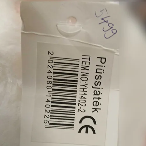 Jouet en peluche blanche en forme d'ours avec un collier rouge clouté de clous en forme d'os.