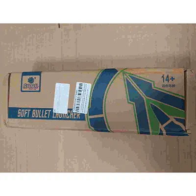 Pistolet à air comprimé en plastique blanc, bleu et noir, avec une paire de lunettes, une cible en carton, quatre obus et dix balles en mousse grise avec ventouses bleues. Produit vendu en ligne, notamment via AliExpress (identifiant unique du produit: 1005009914110938).