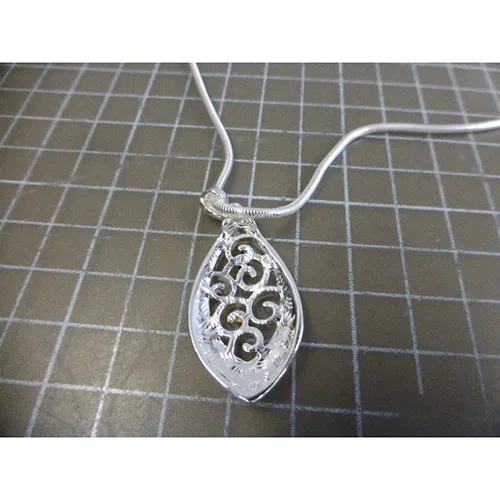 Collier en métal argenté avec pendentifs en métal argenté, noir et doré, fermeture et prolongateur de chaîne.
