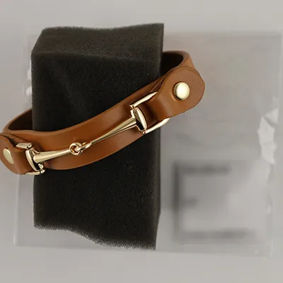 Bracelet en cuir marron, avec des éléments décoratifs en métal doré.
