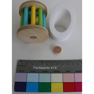 Jeu de jouets en bois composé d'un cylindre avec ses côtés en barres, contenant des boules; une section en bois avec un support pour le cylindre d'un côté et un cylindre rotatif avec un miroir de l'autre côté Produit vendu en ligne notamment via montessoritoddlers.com.