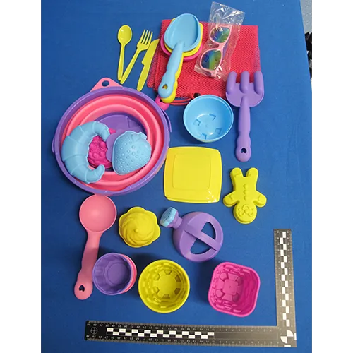 Ensemble de jouets en plastique destiné à la plage composé de 31 pièces dont un seau pliable, un ensemble de couverts (couteaux, fourchettes et cuillères), un filet, des lunettes de soleil, un arrosoir, cinq outils, deux assiettes et 17 moules. Produit vendu en ligne, notamment via Amazon (ASIN B0DSVW25YQ).