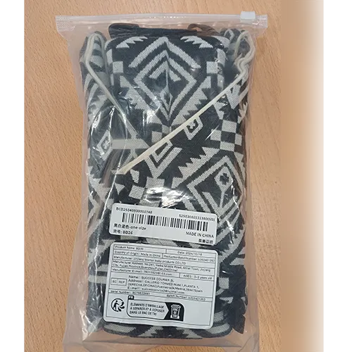Porte-bébé en tissu blanc avec des motifs noirs et une attache en plastique.