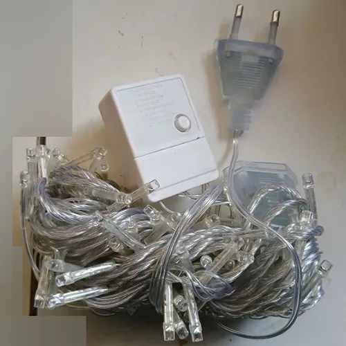 Chaîne d'éclairage décoratif avec 100 LED, câblage transparent et boîtier de commande intégré blanc (modèle: EK-04) avec un bouton de sélection de programme mécanique à l'arrière et un connecteur de bout en bout.