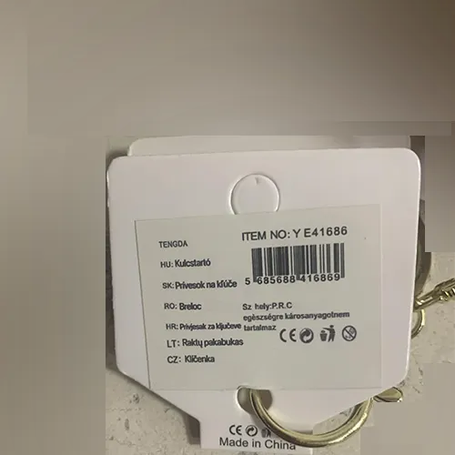 Ours en peluche doux brun clair avec des yeux et un nez en plastique noir, un collier de petites perles sur le cou avec un pendentif en forme de cœur métallique attaché à celui-ci. Un anneau métallique et un mousqueton pour l'accrocher sont fixés au produit.