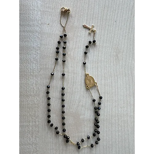 Ensemble de collier rosaire avec des perles de couleur noire, un pendentif rond en métal et une croix en métal.