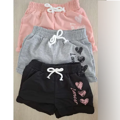 Ensemble de trois paires de shorts destinés aux enfants, de différentes couleurs (gris, rose et noir), avec un motif imprimé sur la cuisse gauche, ainsi qu'un nœud décoratif fabriqué à partir d'un cordon blanc attaché avec un point à la taille. Composition indiquée: 95% polyester, 5% élasthanne.